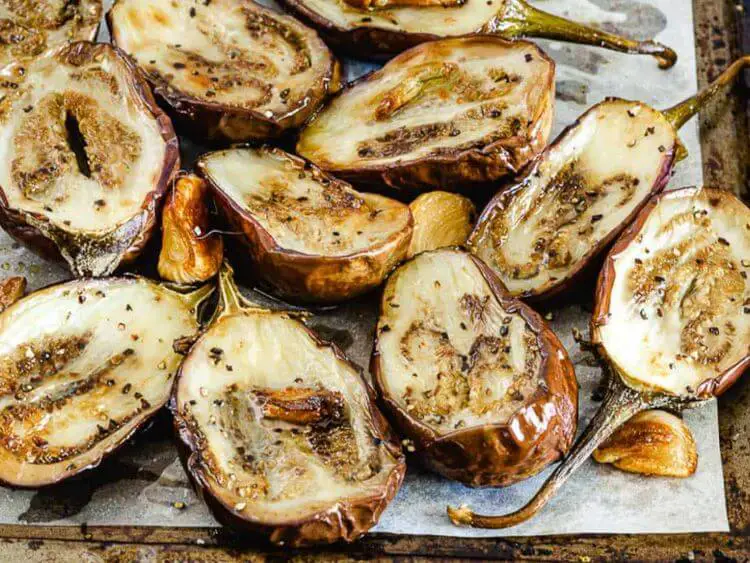 The image shows roasted baby eggplants laid out on what looks to be a baking sheet lined with parchment paper.