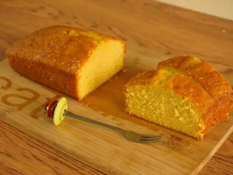 The image shows a homemade pound cake on a wooden cutting board.