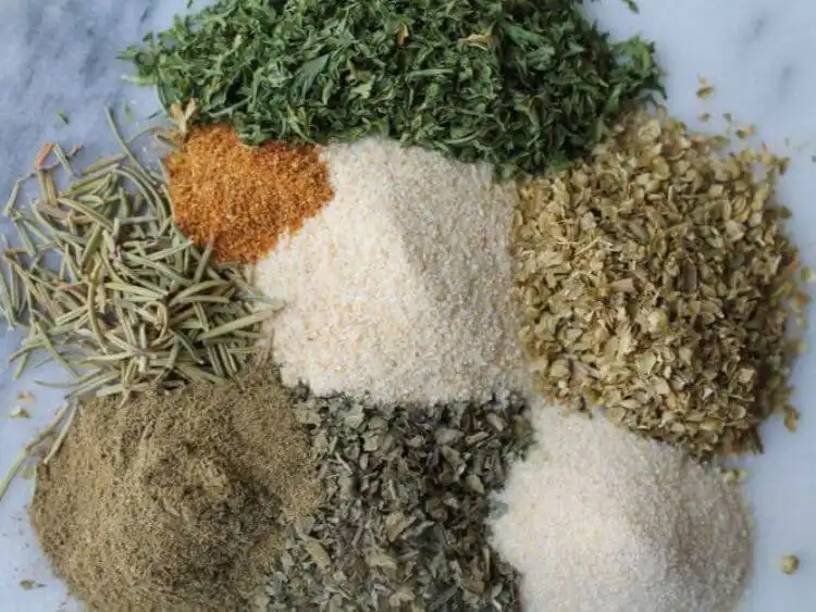 The image displays a variety of dry herbs and spices laid out on a flat surface, likely used for seasoning spaghetti or other Italian dishes.