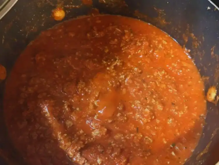 The image shows a close-up view of a pot containing what appears to be a tomato-based sauce.