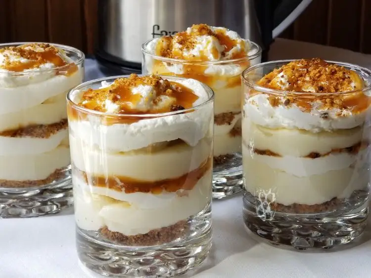 The image shows a dessert that appears to be banana pudding, served in clear glass cups which allows the layered composition to be viewed.