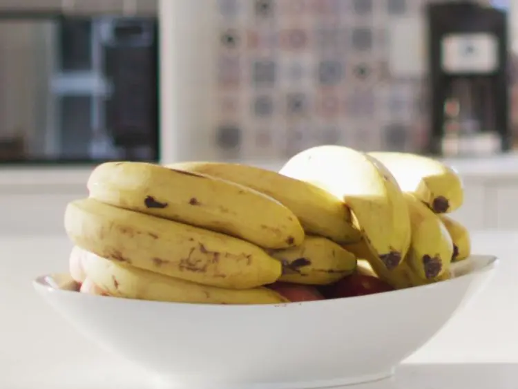 The image shows a bunch of ripe bananas with some brown spots indicating their ripeness.