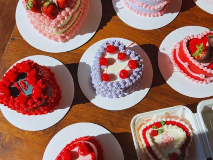 The image shows a table with a variety of heart-shaped cakes on it