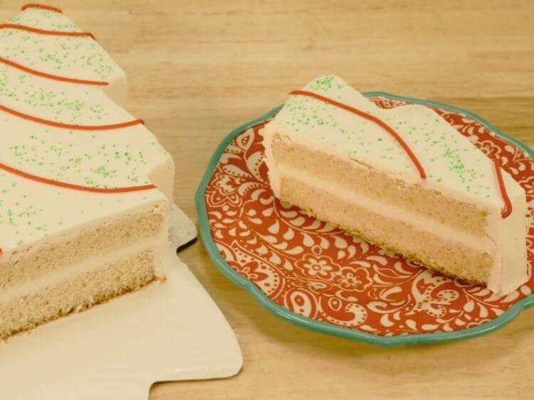 The image shows a slice of cake on a plate next to a slice of cake in a Christmas tree pan