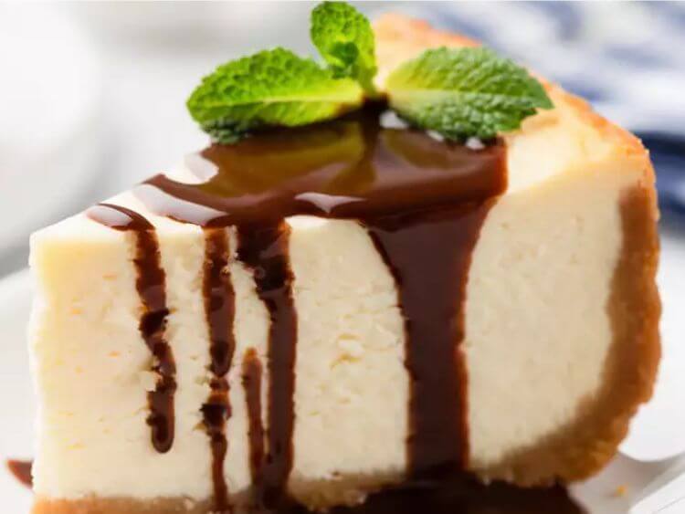 The image shows a slice of keebler cheesecake topped with chocolate sauce.