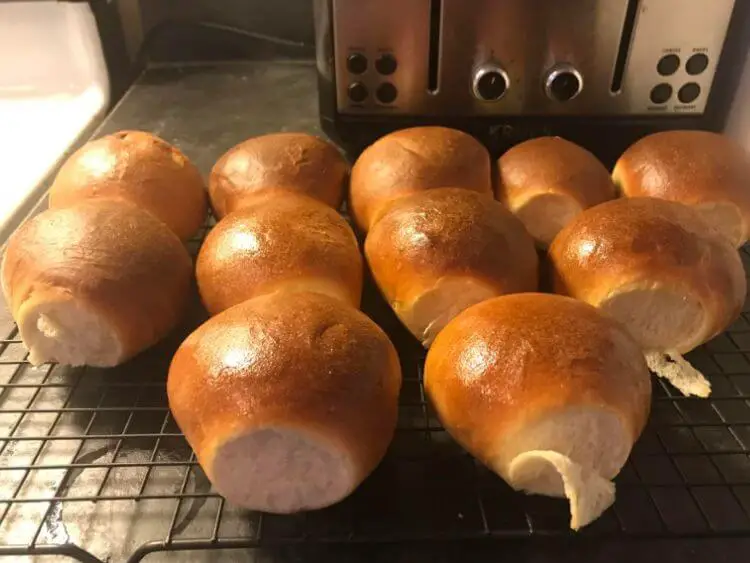 golden brown bread rolls sitting on a wire cooling rack in front of a toaster oven