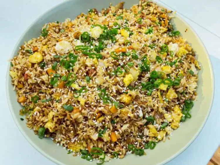 white bowl filled with rice and vegetables, topped with sesame seeds