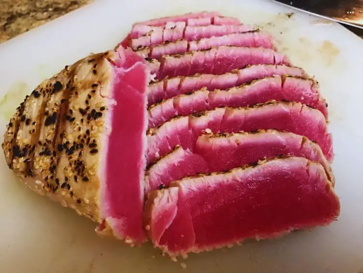 The image shows a close-up of sliced tuna on a cutting board