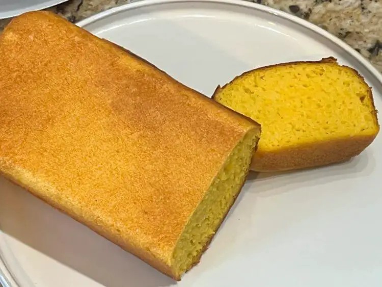 The image shows a loaf of mango bread on a light blue plate.