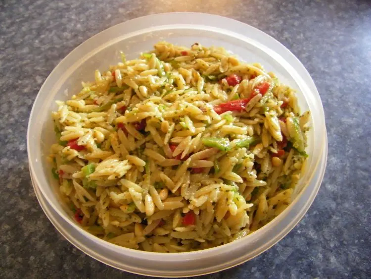 a bowl of orzo pasta mixed with what appears to be pesto sauce.