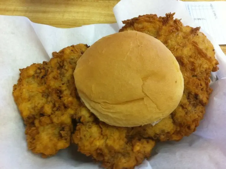 a sandwich that consists of a large, breaded and fried piece of steak that extends well beyond the edges of the bun, placed on a simple hamburger bun.