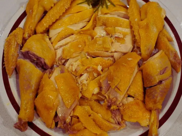 a plate of steamed chicken that has been chopped into pieces.
